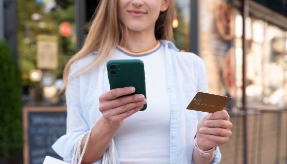 femme-carte-banquaire-telephone-dehors-shopping