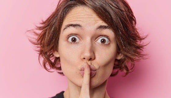 surprised-young-european-woman-stares-bugged-eyes-makes-silence-gesture-spreads-rumors-has-trendy-hairstyle-tells-secret-isolated-pink-studio-background-body-language-shushing-concept (1)